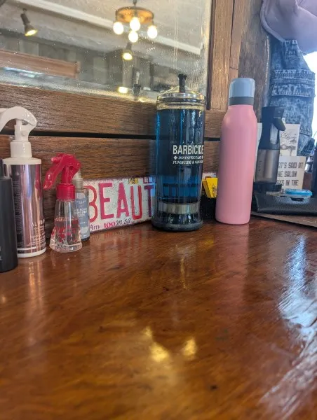 A styling station at Hair Etc.: a polished wooden counter with spray bottles, a Barbicide jar and a vintage "Beauty" sign